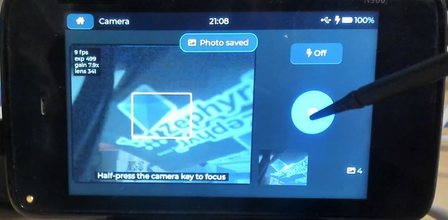 Camera app showing a live preview, focus box, photo thumbnail and Photo saved toast
